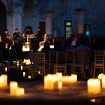 il chiostro dei domenicani illuminato dalle luci delle candele durante un concerto tributo a Ennio Morricone